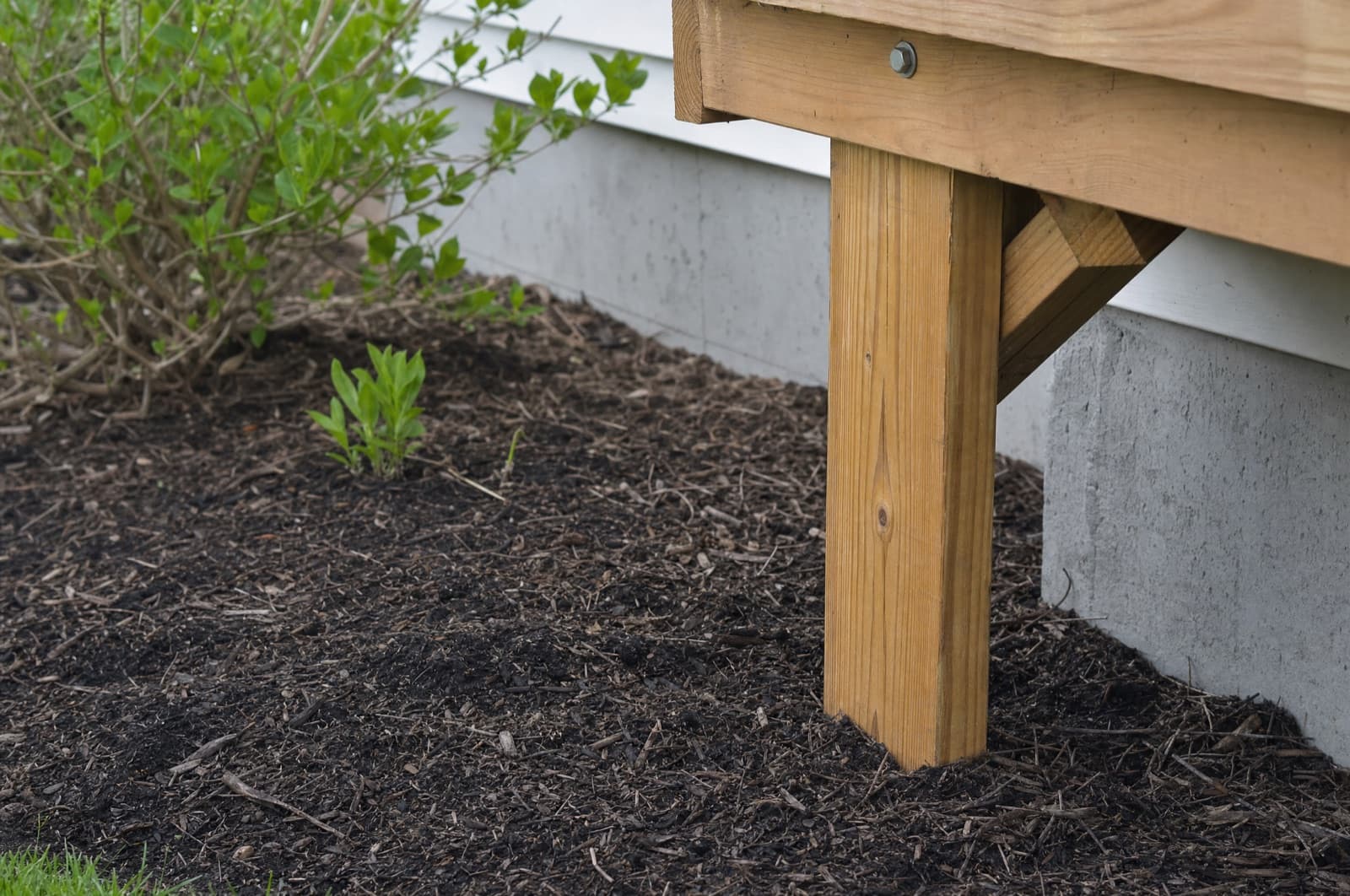 A woodpile bridging soil and the foundation — the condition behind termite pressure